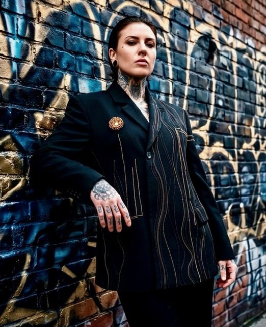 Model in een custom krijtstreep-blazer tegen een graffitimuur.