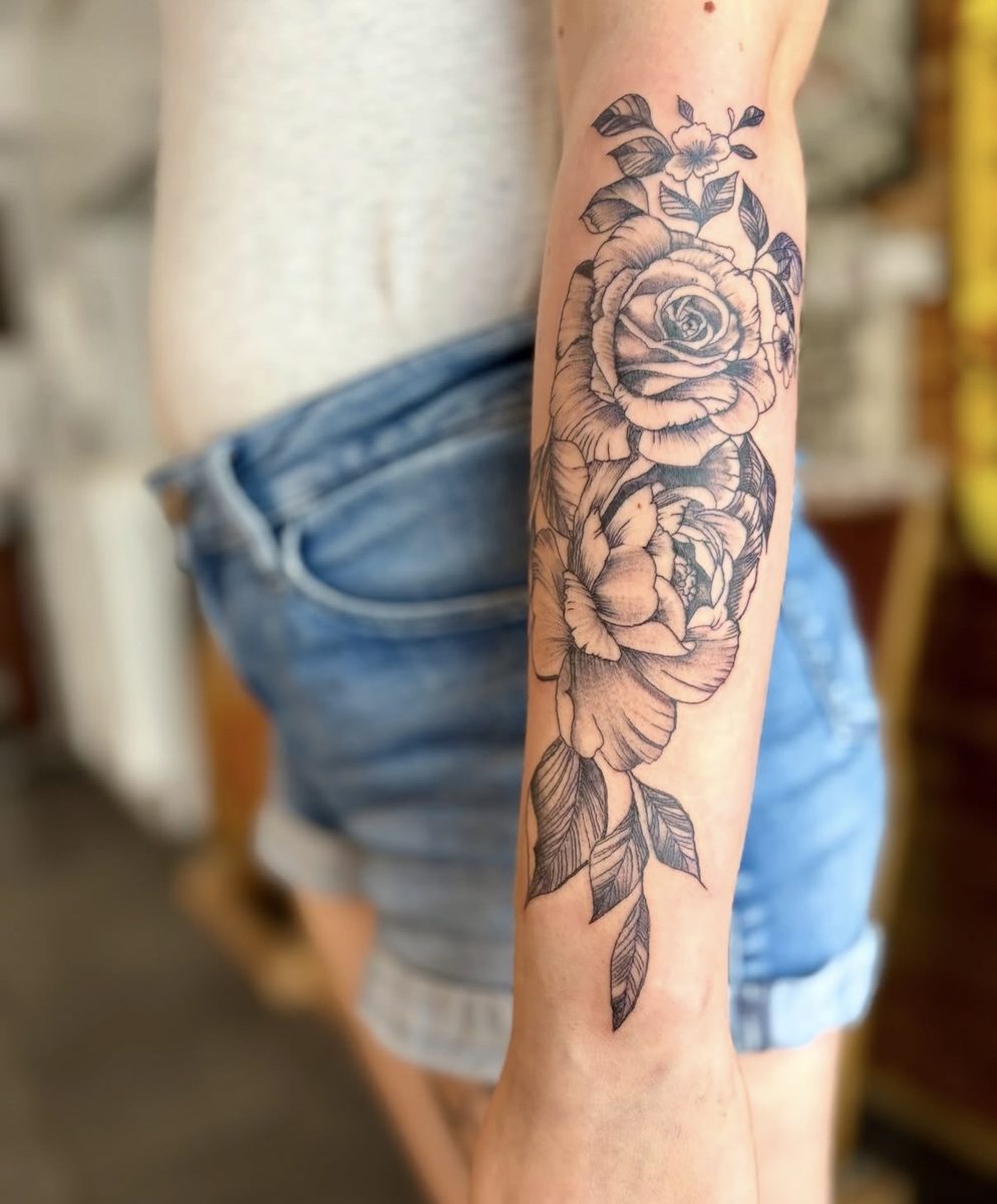 Roos op de onderarm in zwart-grijs — voorbeeld van floraal werk.